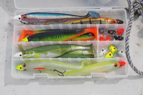 Köderbox mit bunten Gummifischen und Jigs, bereit für das Schleppen auf Hecht.