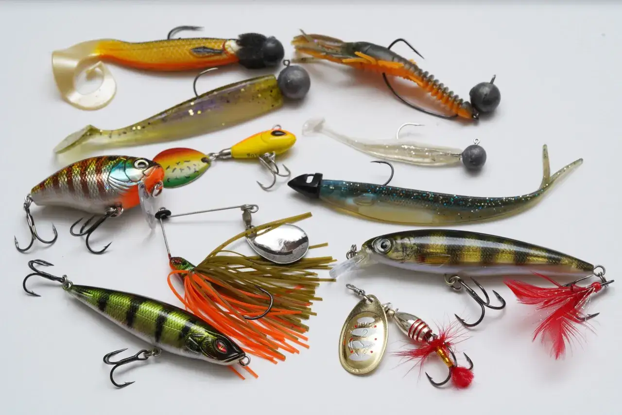 Vielf&auml;ltige Kunstk&ouml;der f&uuml;r das Barschangeln im Winter: Gummifische, Wobbler und Spinner in verschiedenen Farben und Formen.