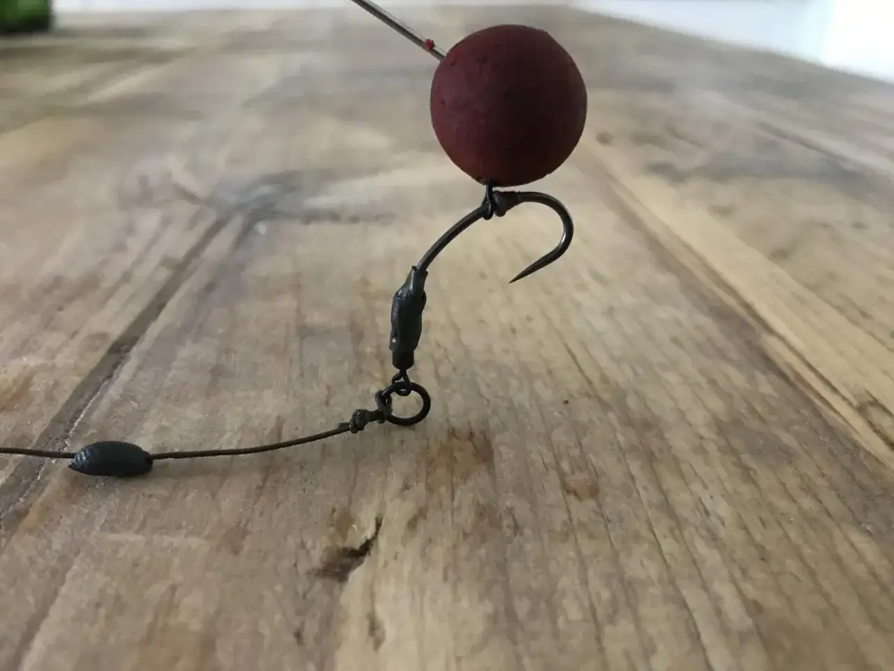 Ein Pop-up-Montage-Detail: Roter K&ouml;derball auf einem Haken, bereit f&uuml;r den Fang.