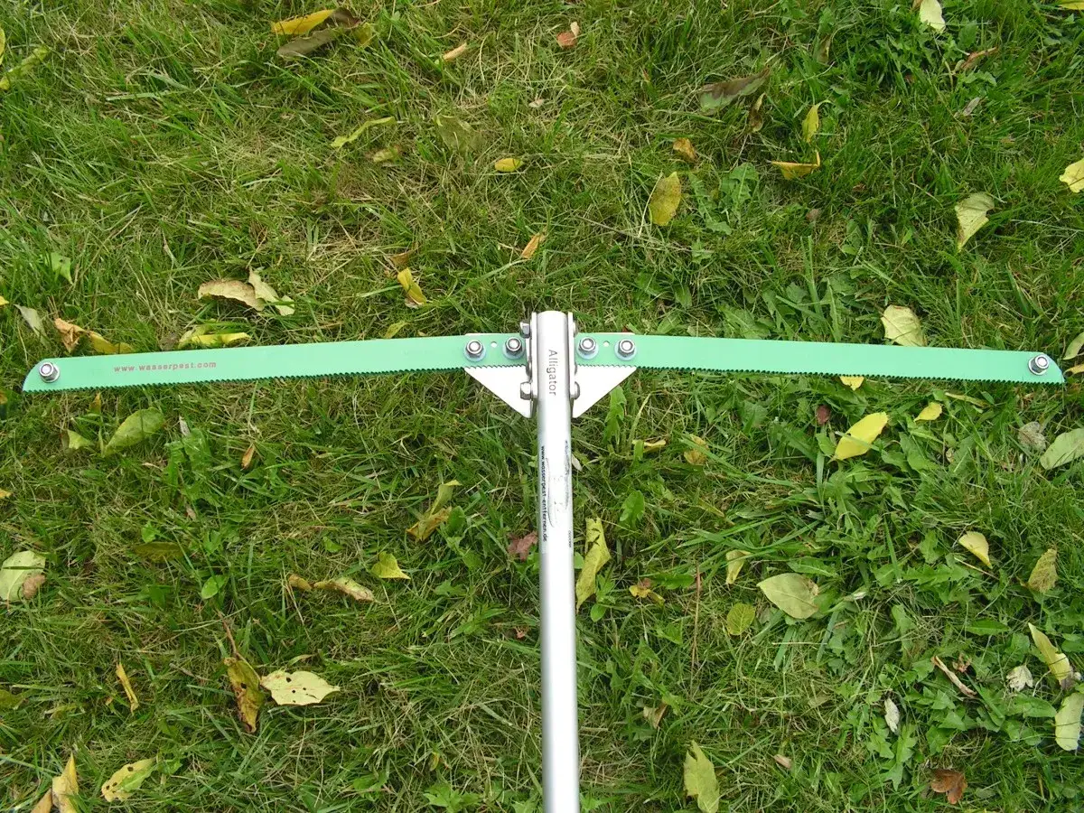 Grünes Werkzeug mit Sägezahnung zur Entfernung von Wasserpest im Teich.