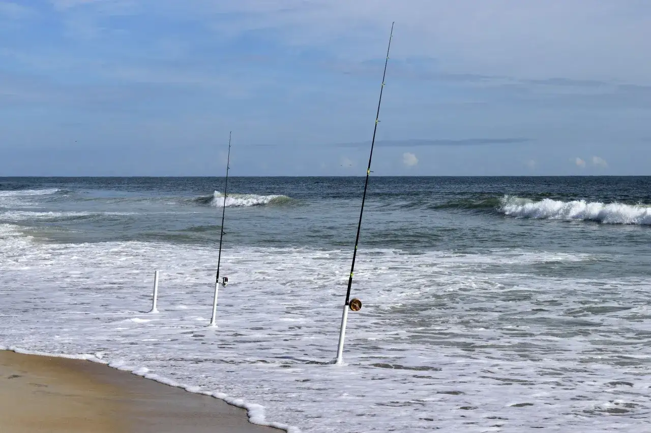 Drei Angelruten stehen im Wasser für Nordsee Angeln vom Ufer. Die Wellen brechen am Strand.