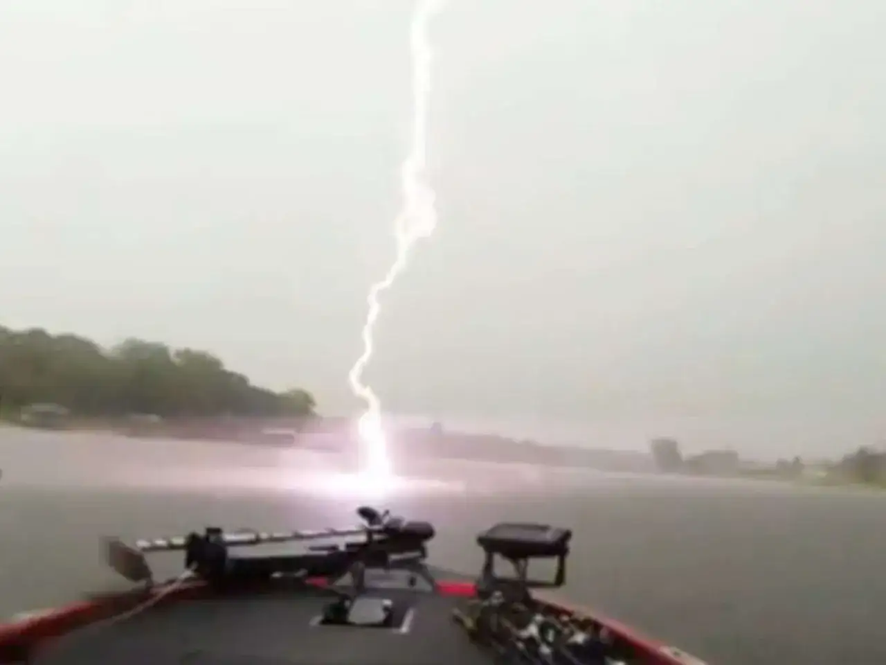 Blitz schl&auml;gt ins Wasser, w&auml;hrend jemand auf einem Boot angelt nach Gewitter. Die Szene ist dramatisch und gef&auml;hrlich.