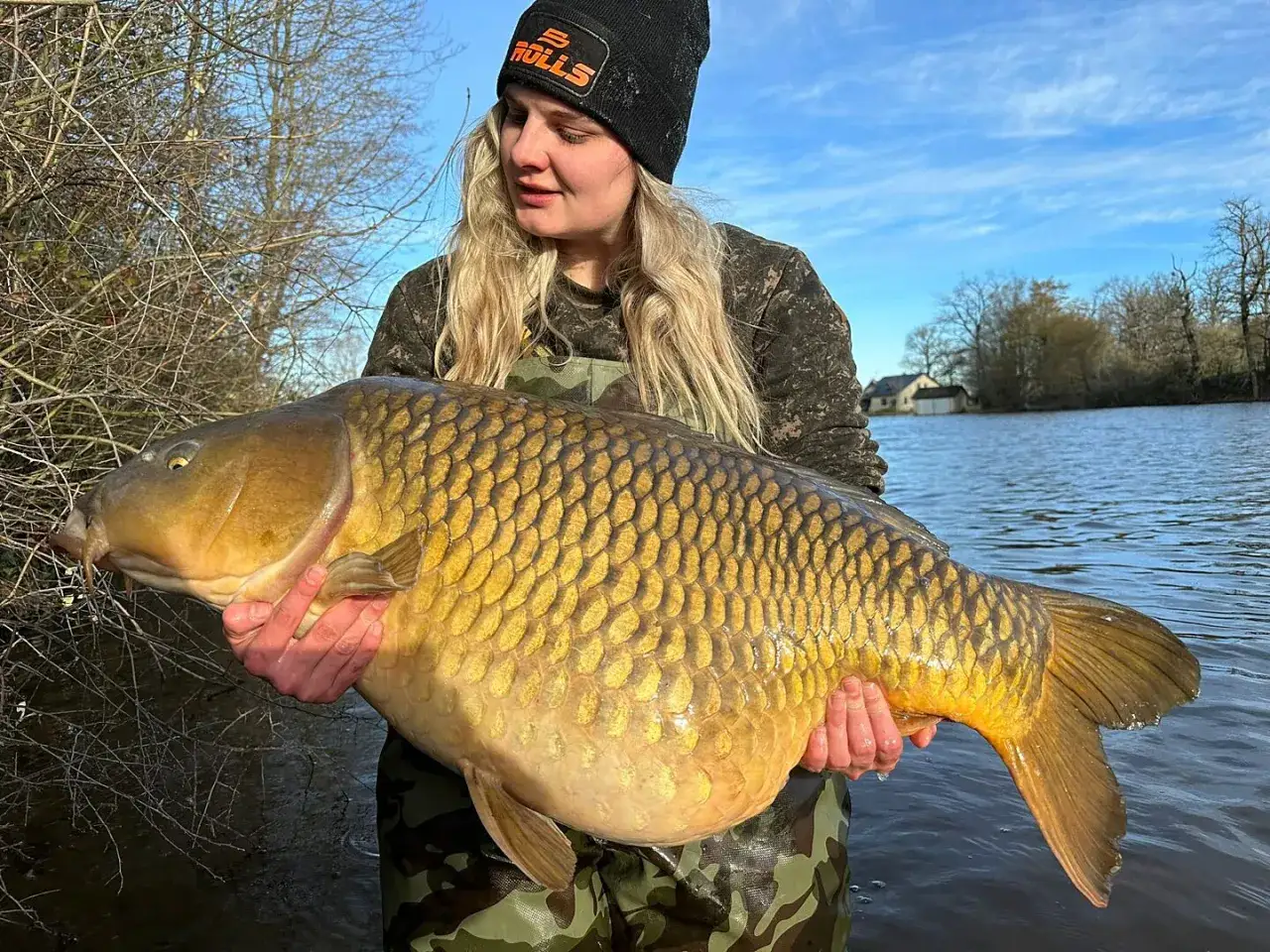 Eine Anglerin hält stolz einen riesigen Karpfen am Paylake in Frankreich.