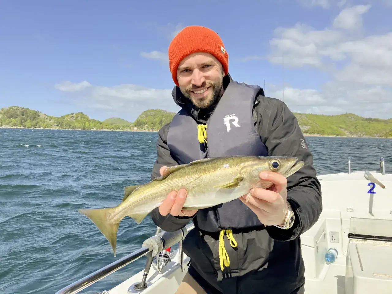 Glücklicher Angler mit frisch gefangenem Fisch vor der Küste von Farsund. Ein perfekter Fang an einem der vielen Farsund Angeln Hotspots.